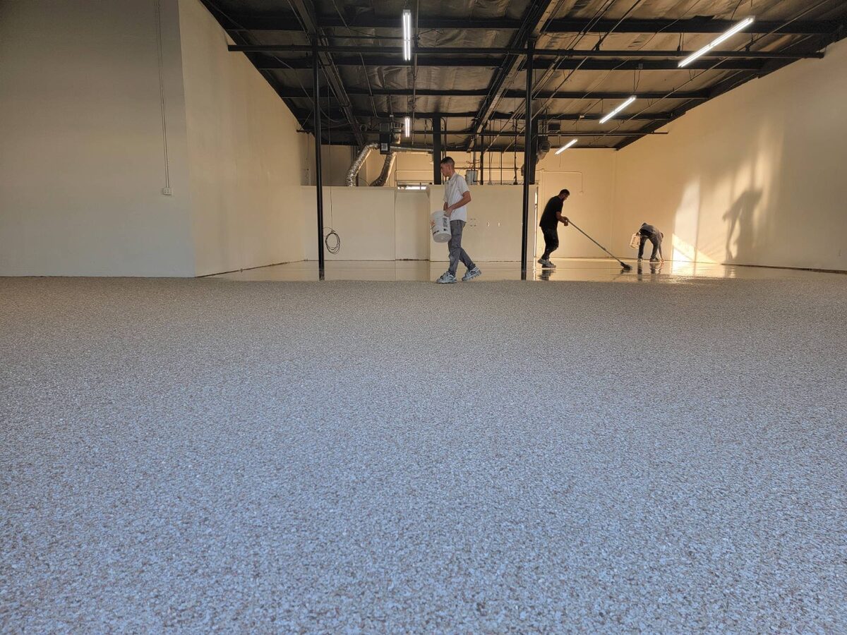 Primo Epoxy Flooring installation crew applying a decorative flake commercial epoxy floor in a large warehouse space